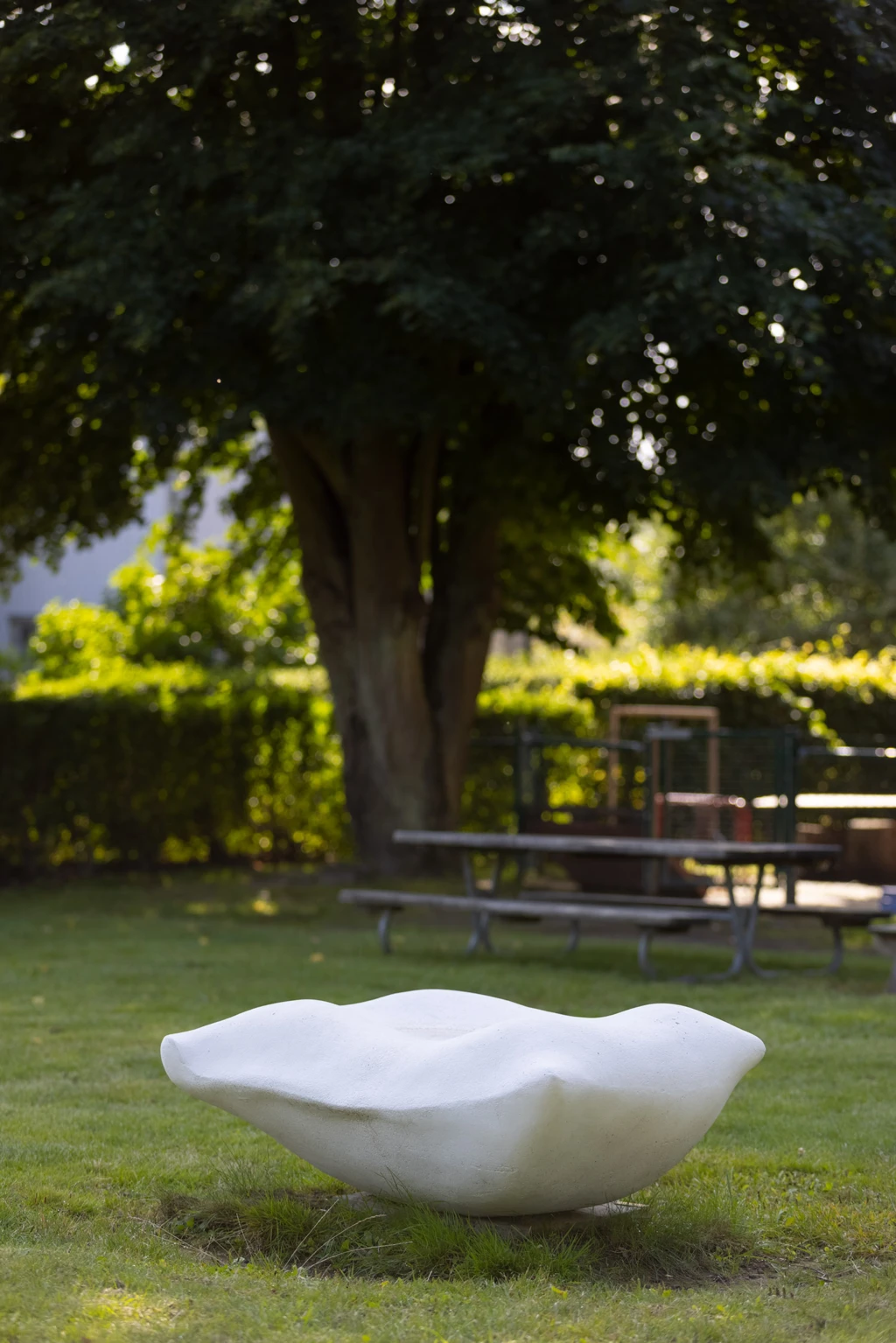 Bild av en vit kudde gjuten i betong. Placerad i en trädgård.