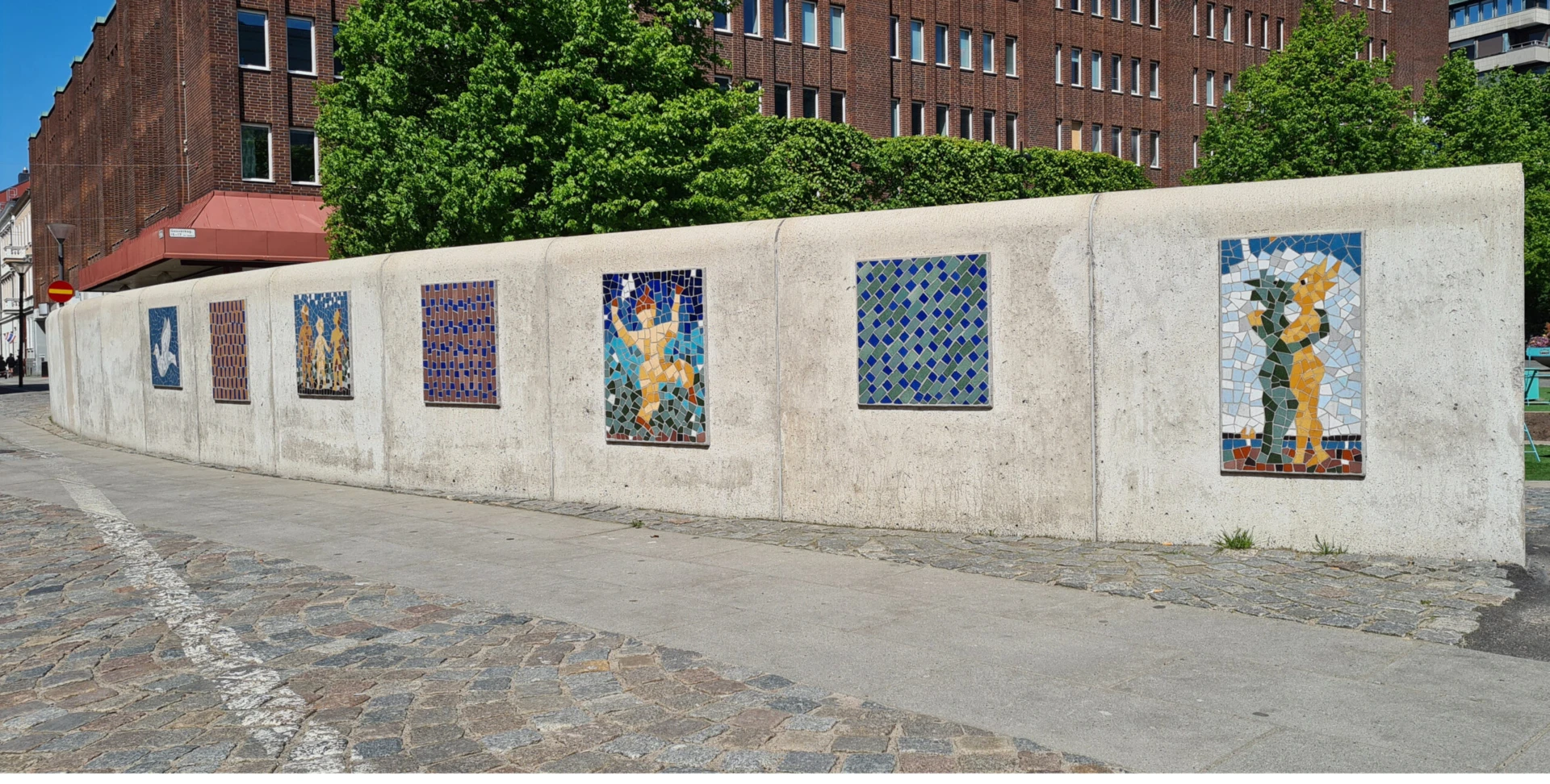 Grå mur med färgglada mosaiker på.