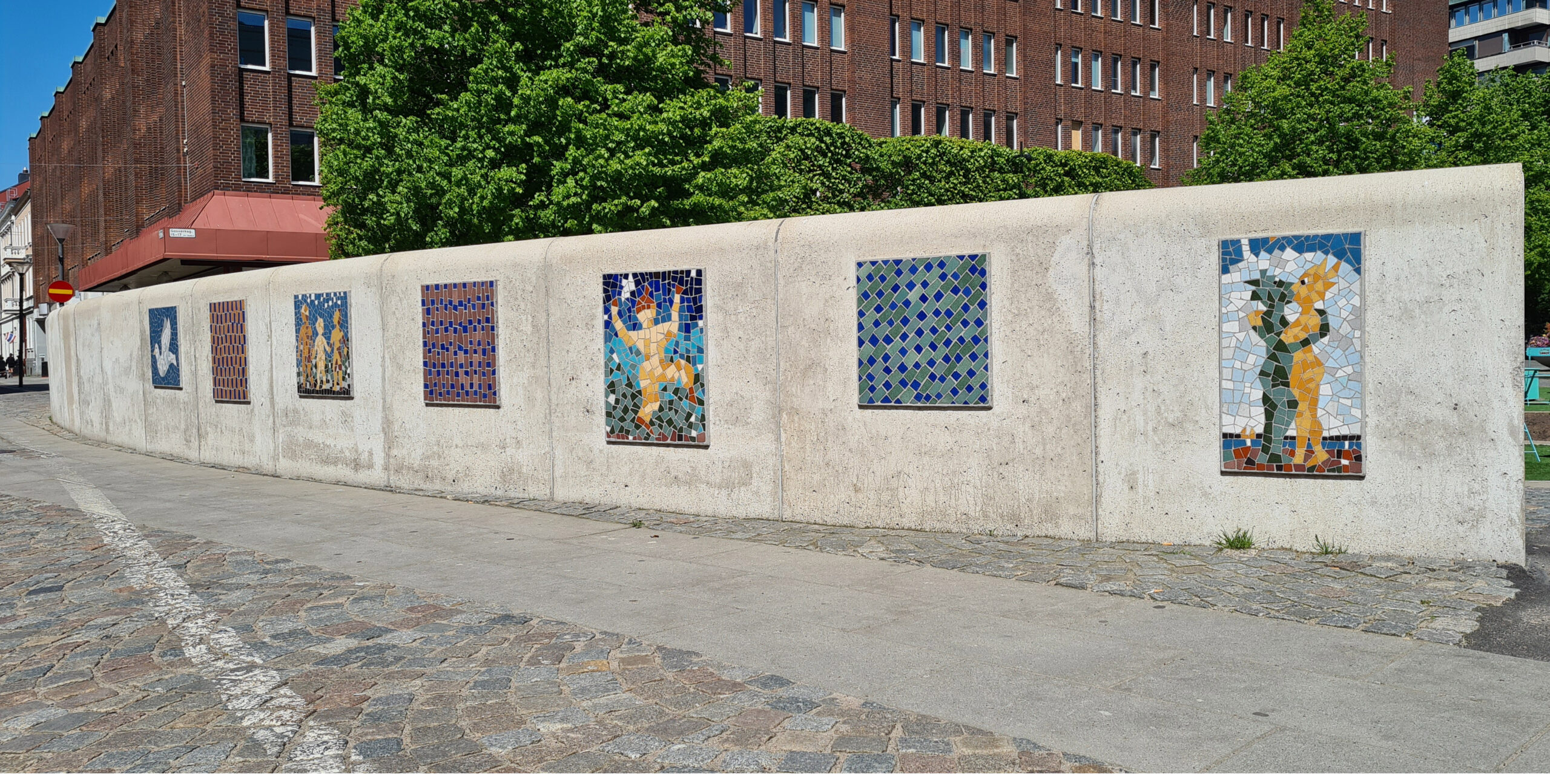 Grå mur med färgglada mosaiker på.