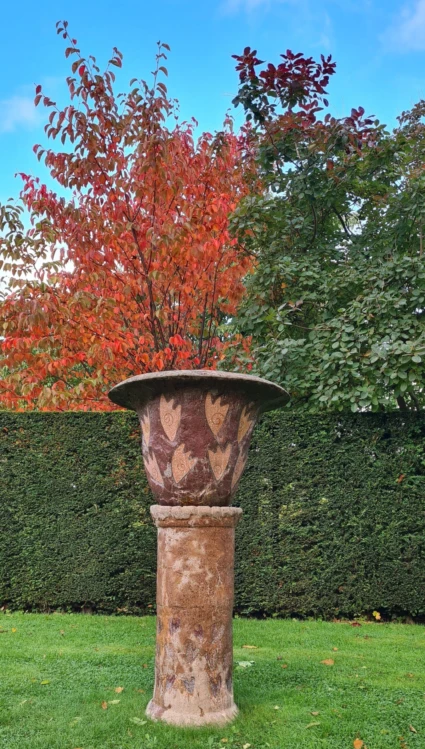 Urna på pelare gjord i terrazzo och terracottafärgad betong.