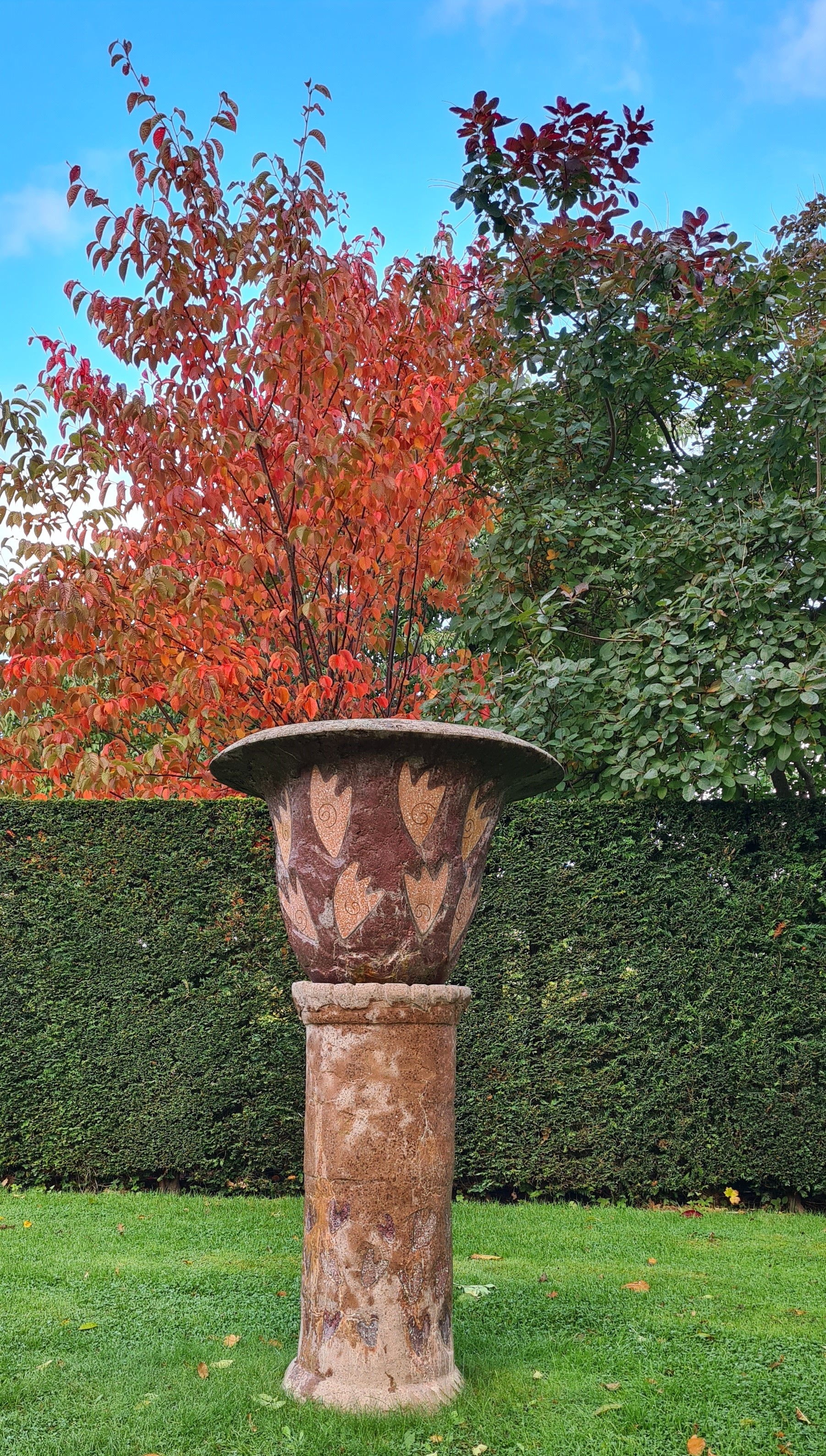 Urna på pelare gjord i terrazzo och terracottafärgad betong. 