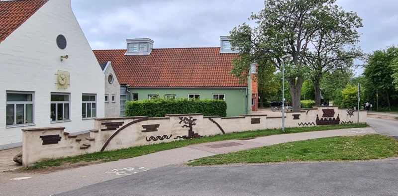 Utromhusbild med ljus mur med reliefer, bland annat ett vikingaskepp. Relieferna är gjorda i saltglaserat stengods.