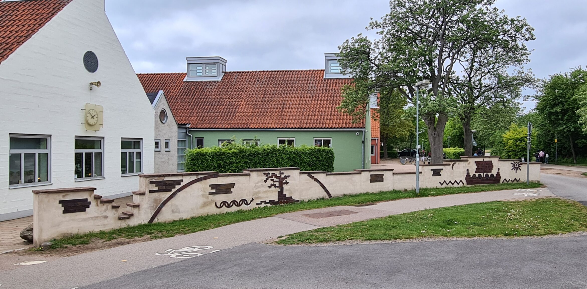 Utromhusbild med ljus mur med reliefer, bland annat ett vikingaskepp. Relieferna är gjorda i saltglaserat stengods.