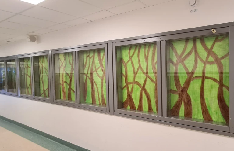 Interiör med fönster som målats som skog med bruna stammar.