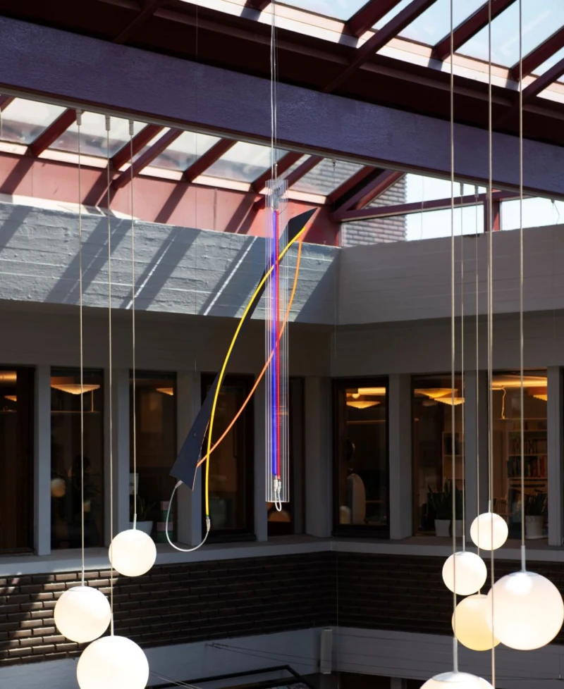 Interiör med glastak där skulptur med neonrör hänger från taket. 