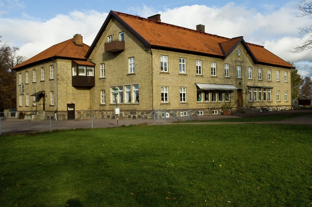 Utomhusbild på byggnad i gult tegel med 2,5 våningar.