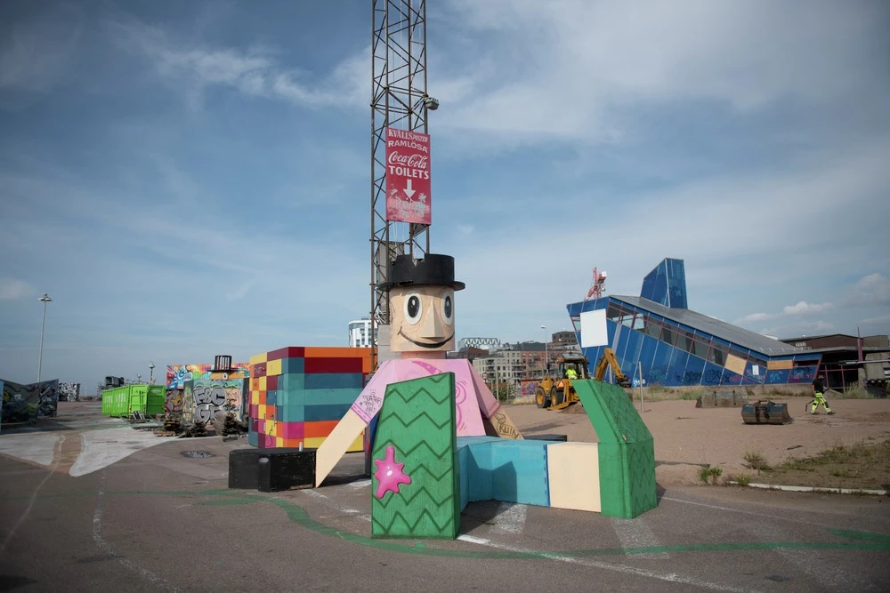 Utomhusbild av en skulptur av en glad gubbe i hamnmijö.