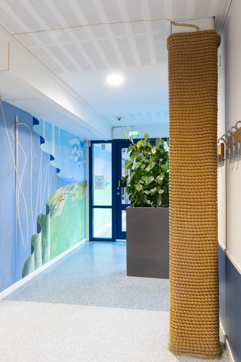 Interiör med pelare inlindad i rep, repet gör över väggen ner på andra sidan och bli en tråd som syr ihop land och himmel. 