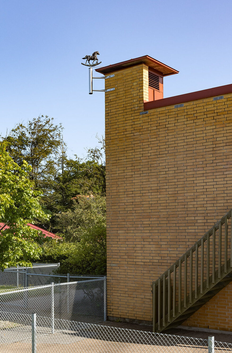 Hörn av tegelbyggnad med konstverket sittande högst upp i hörnet.