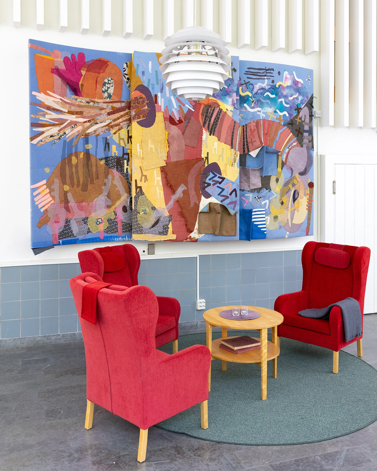 Interiör med stor applikation främst i rött, guld och blått.