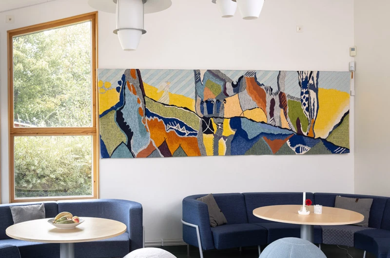 Interiör med väggtextil i abstrakta former, En liten ängel syns gå längs en linje. 