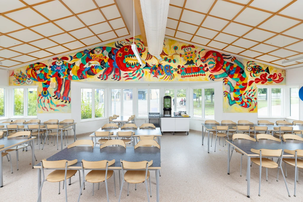 Matsal där väggen är fylld med en målning i starka grundfärger.