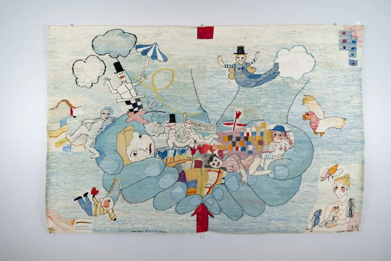 Textilvävnad i ljusblå toner med figurer och två stora händer som håller dem. 