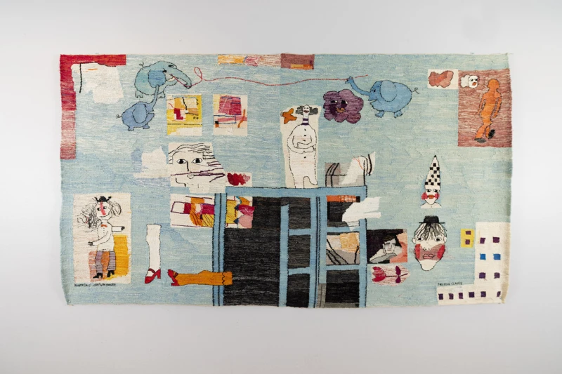 Konstvävnad i ljust blå med en massa utspridda figurer, elefanter, clowner, ansikten mm. i naiv stil. 