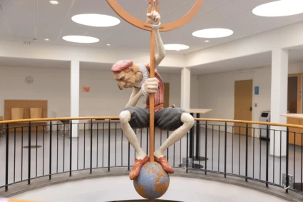 Målad träkulptur av Tycho brahe som hänger från taket över en öppning mellan våningarna.