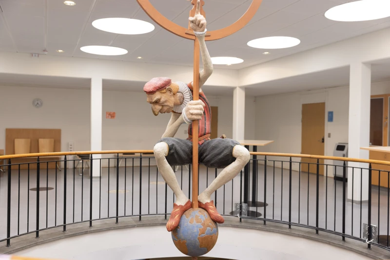 Målad träkulptur av Tycho brahe som hänger från taket över en öppning mellan våningarna.