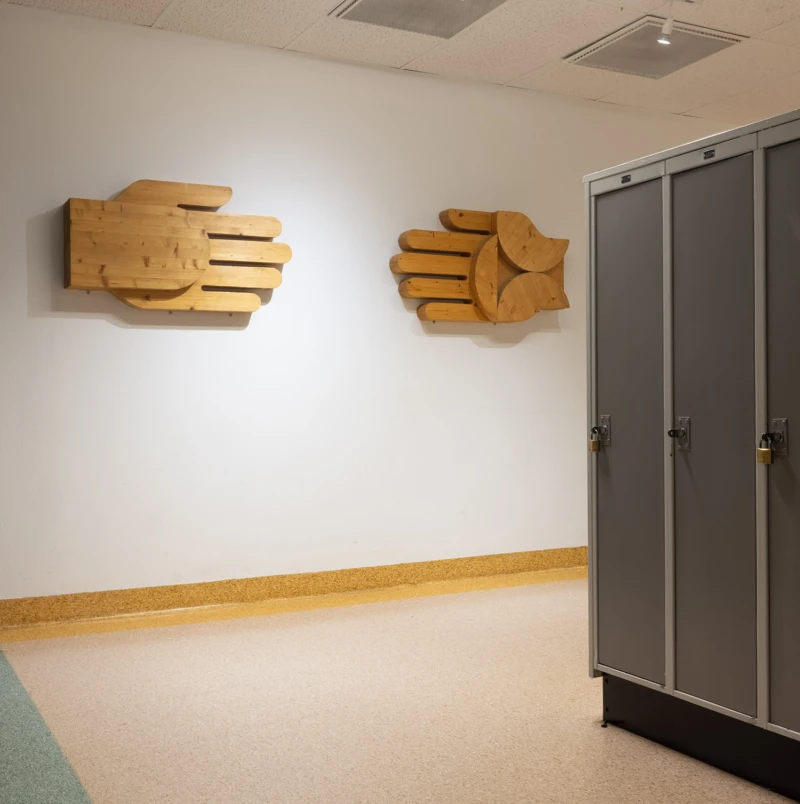 Interiör med två stiliserade händer i utsågat trä.