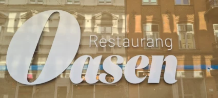 Fönster med Oasens namn på i vit fönsterfolie.