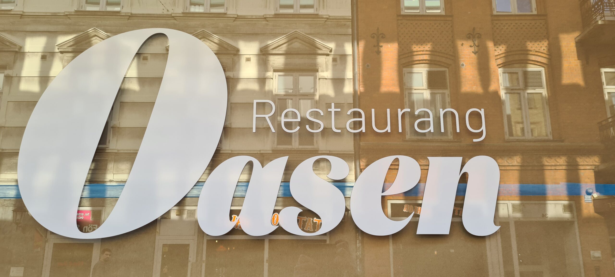 Fönster med Oasens namn på i vit fönsterfolie.