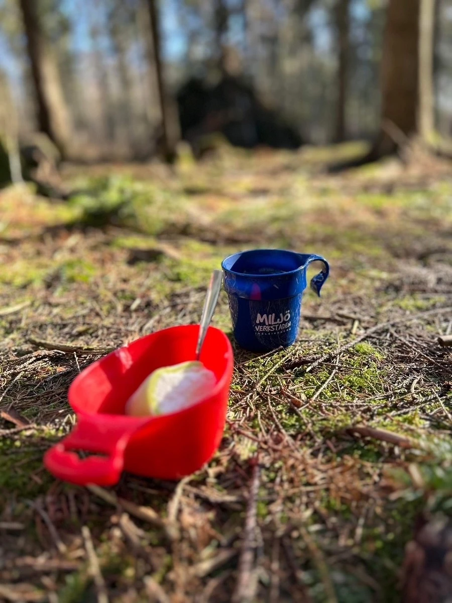 Bild på kaffemugg och fika i skogen