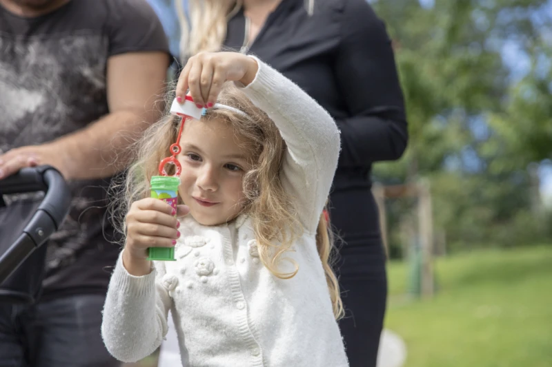 Drottninghög 2019-06-16. Familj med barnvagn promenerar, dotter blåser såpbubblor.