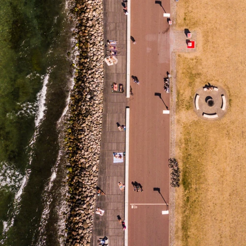 En drönarbild. Vi ser en löparbana och en solbränd gräsmatta under oss. Människorna där nere är små som myror.