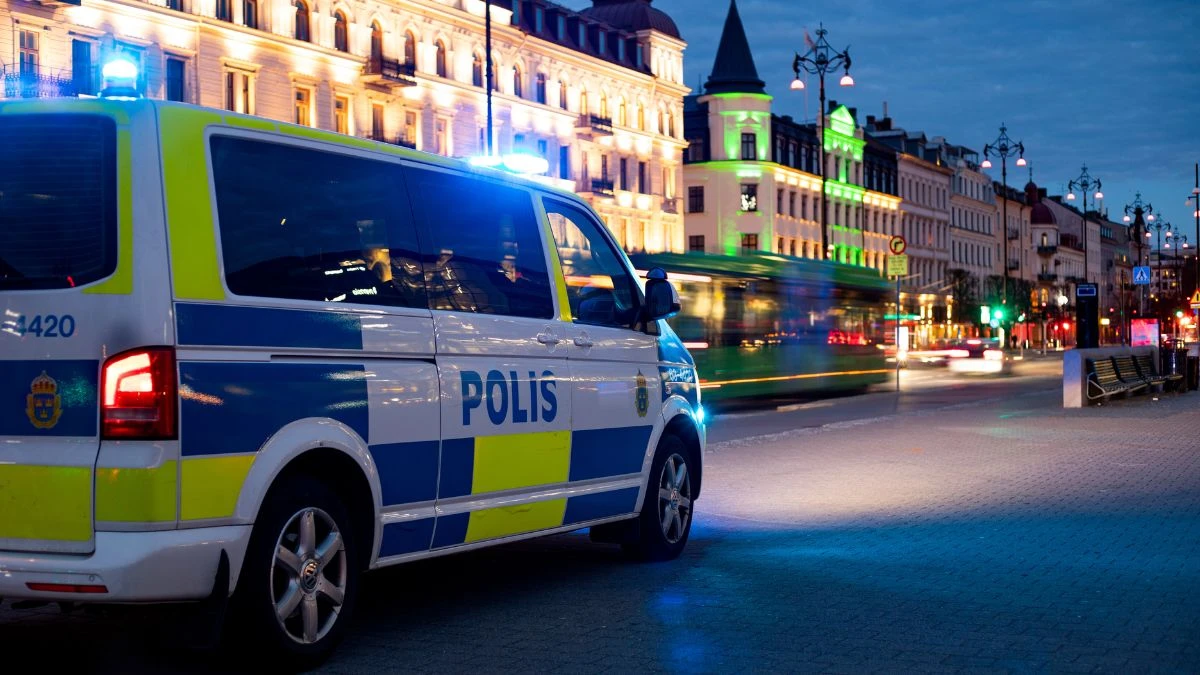 En polisbuss med påslagna blåljus kör längs en kvällsbelyst Järnvägsgatan i Helsingborg.