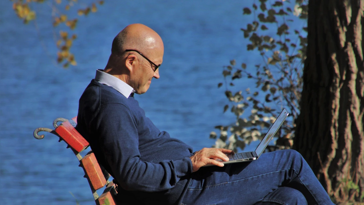 Sneior med laptop utomhus.