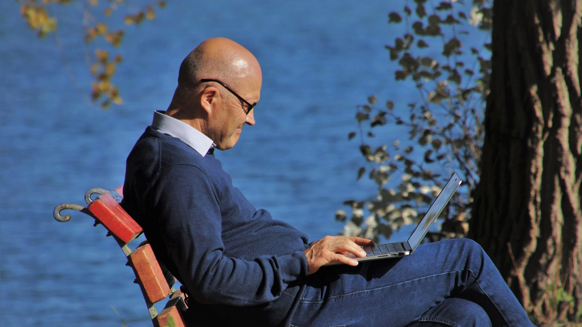 Sneior med laptop utomhus.