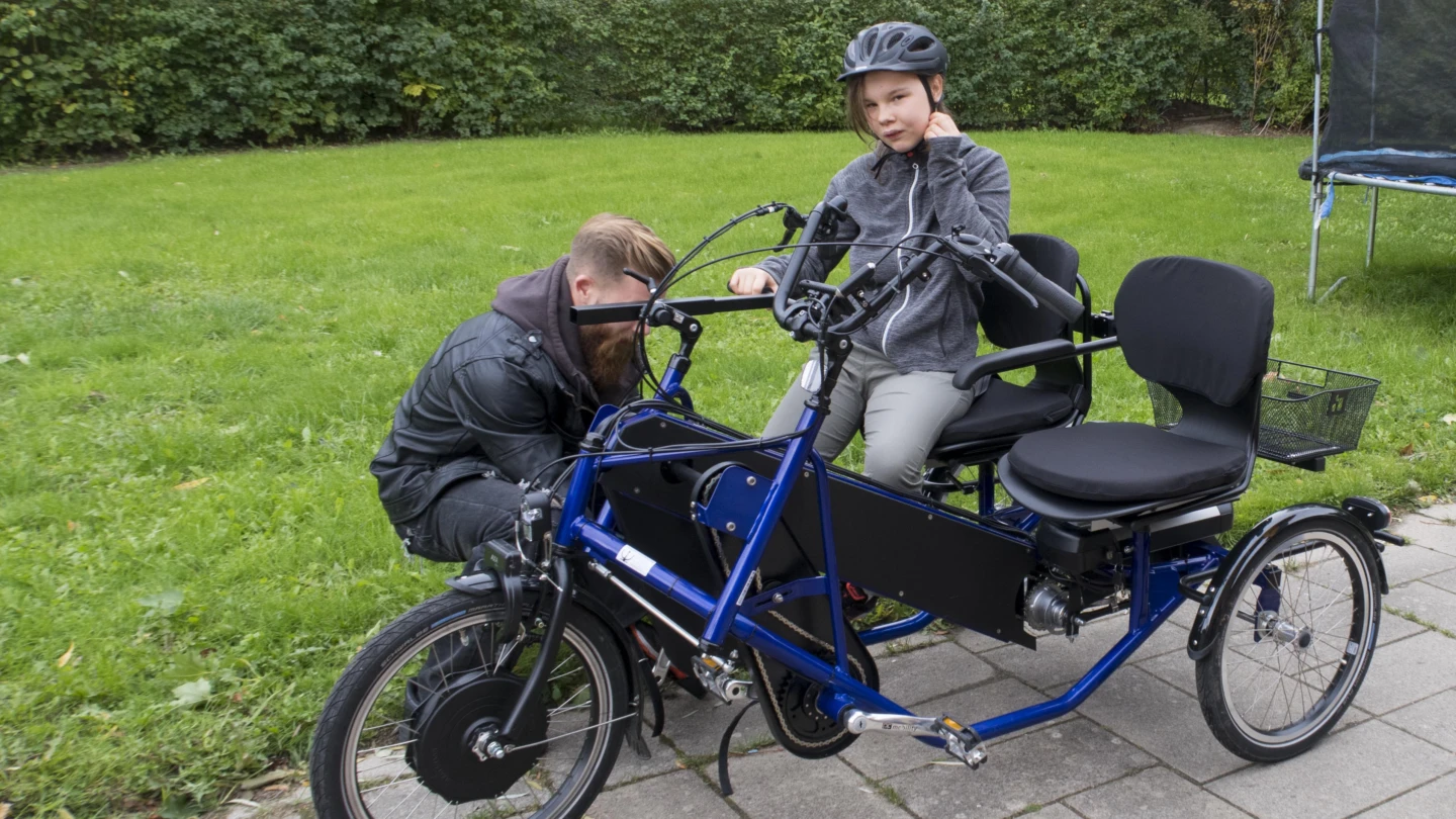 en man böjer sig ner och hjälper en flicka med hennes fot på cykelpedalen