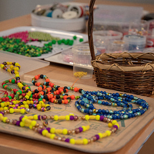 Vi har pärlor i flera olika färger som vi tillverkar halsband och armband med.