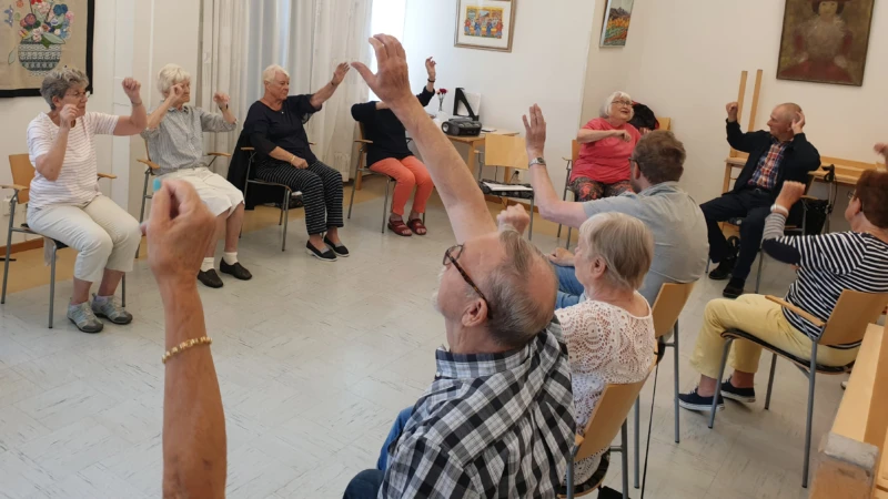 Kerstin leder Balansera-mera gymnastiken där deltagarna utför rörelser till musik.