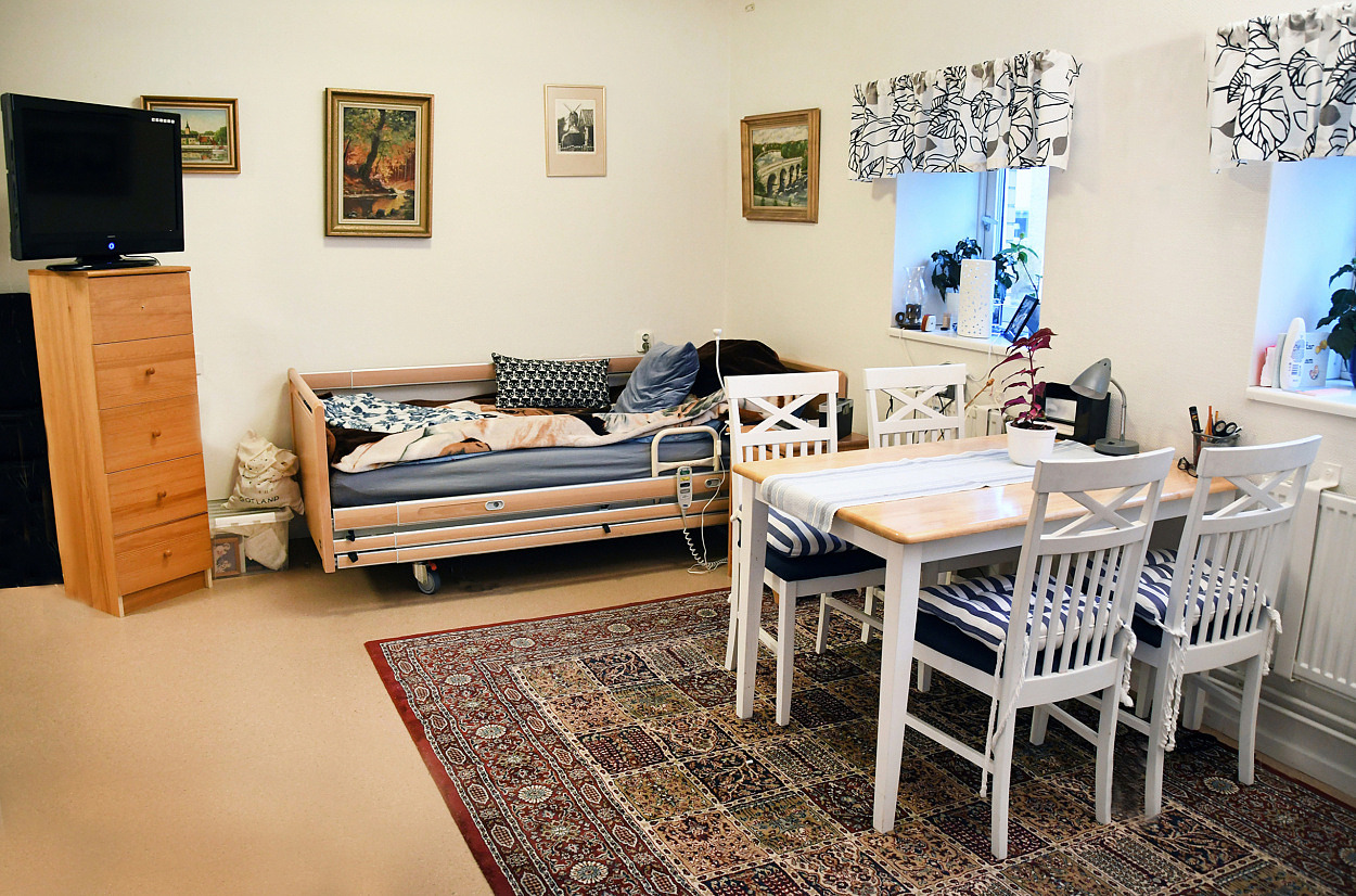 En lägenhet med säng, vitt matbord och fyra stolar.