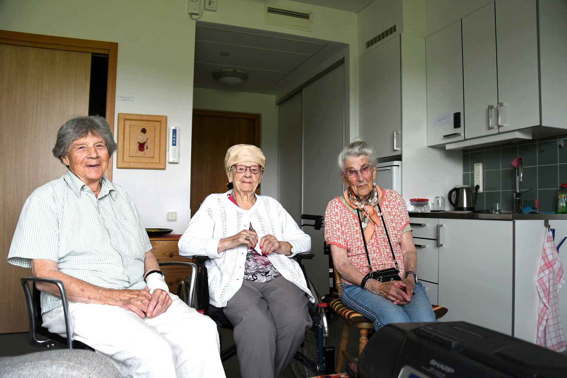 Tre äldre damer sitter bredvid varandra och ser glada ut