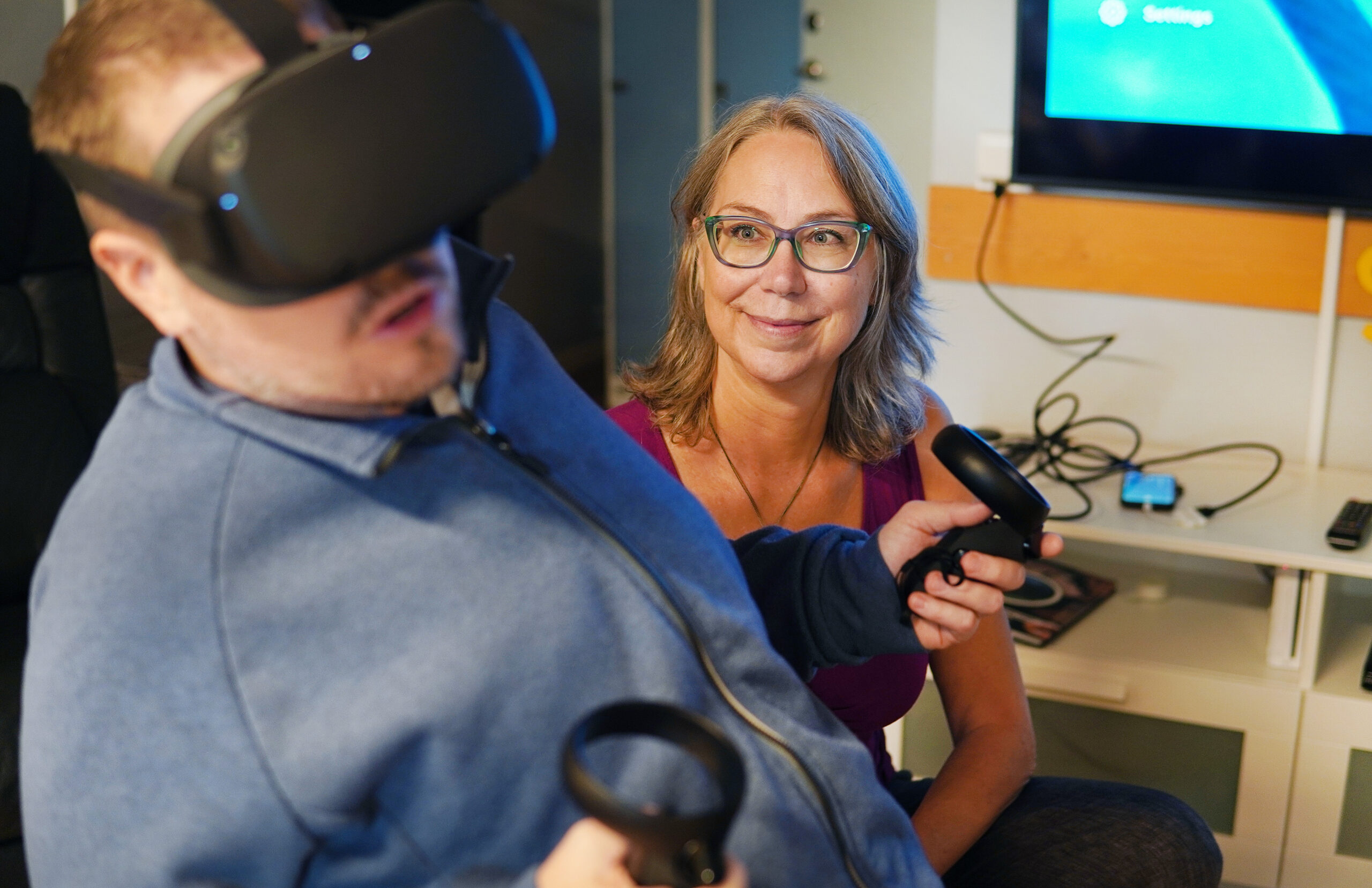 En kvinna ler och tittar på en man som har VR-glasögon på sig.