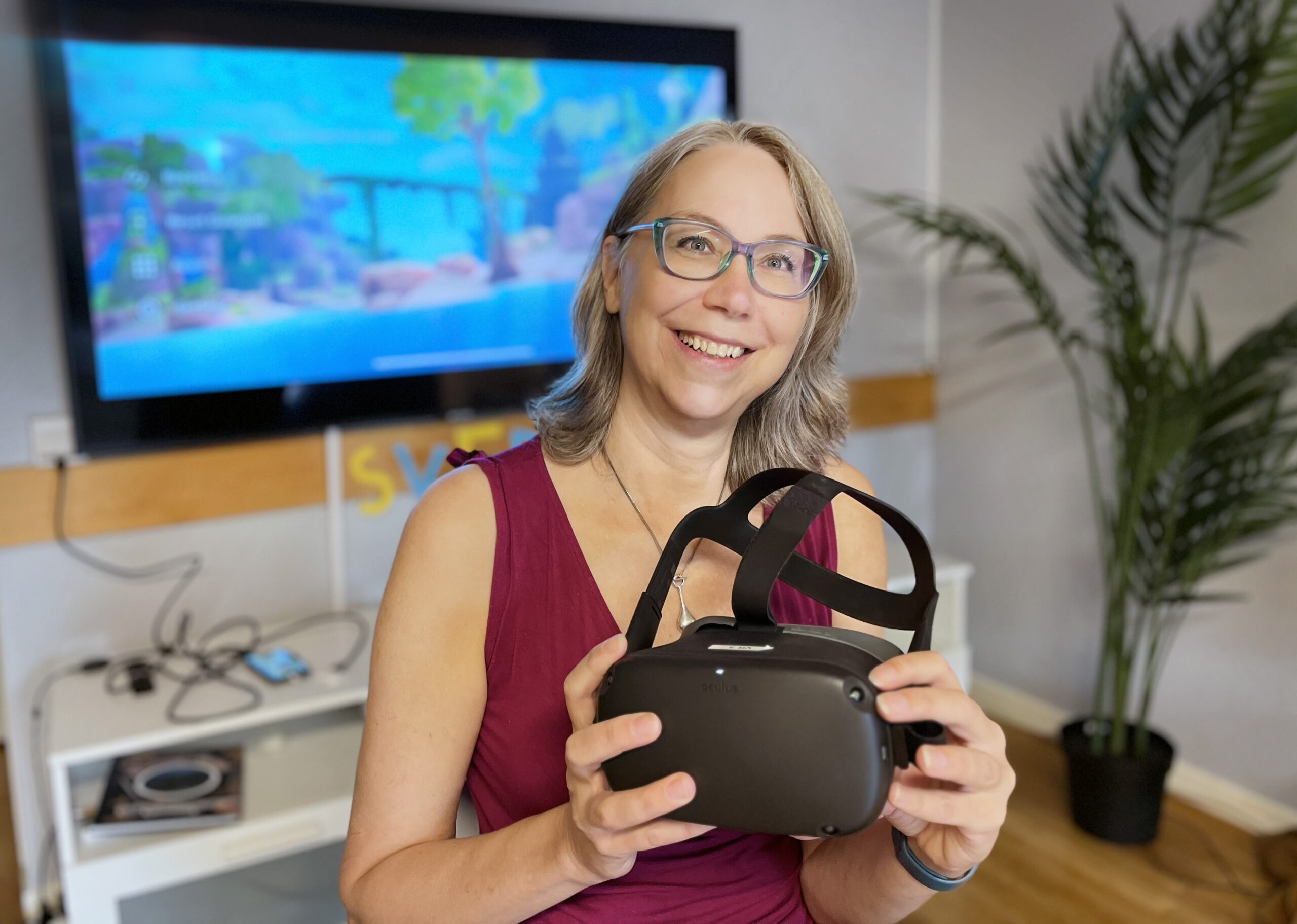 Kvinna tittar in i kameran och håller i ett par VR-glasögon.
