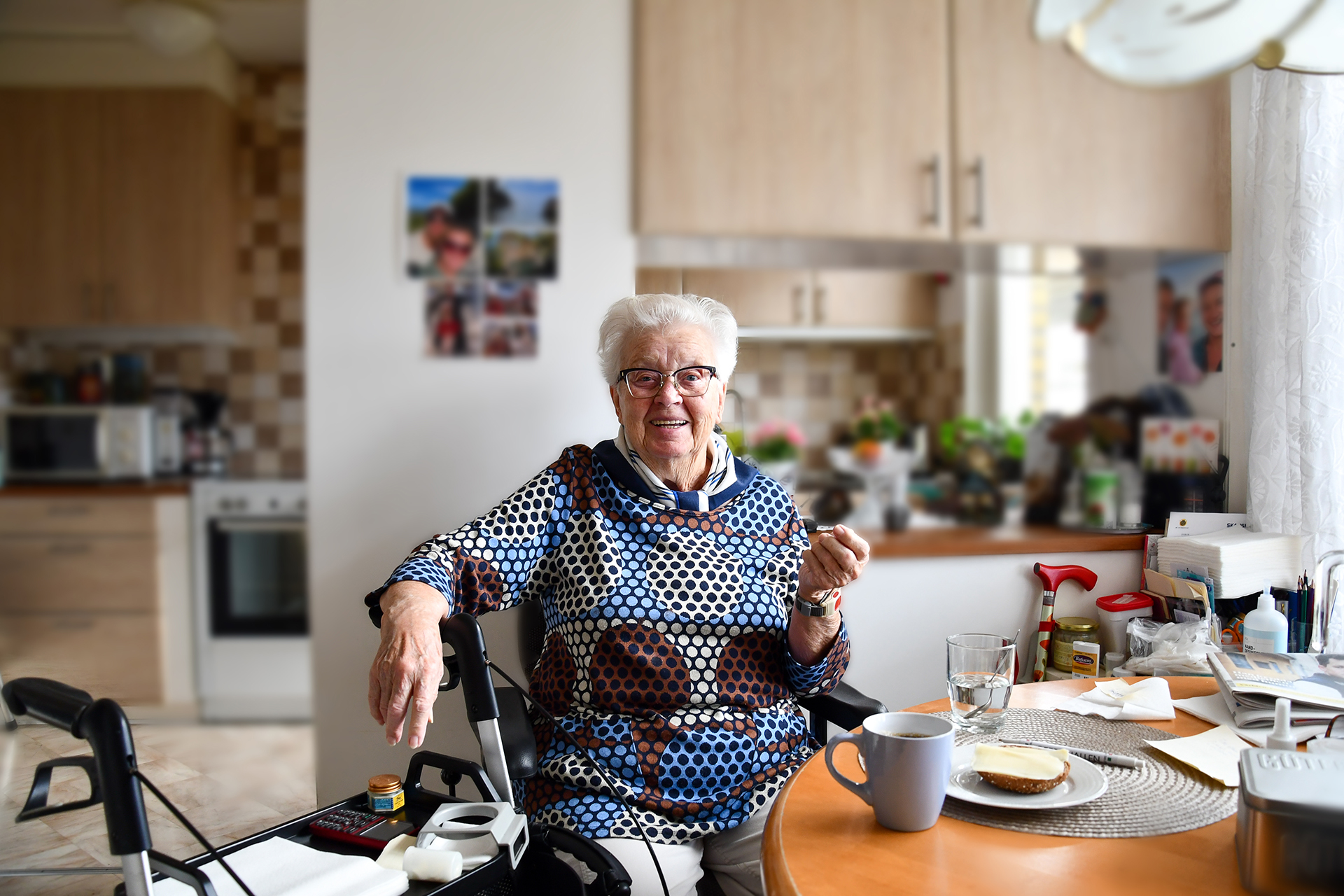 Senior kvinna sitter vid ett bord med en rullator.