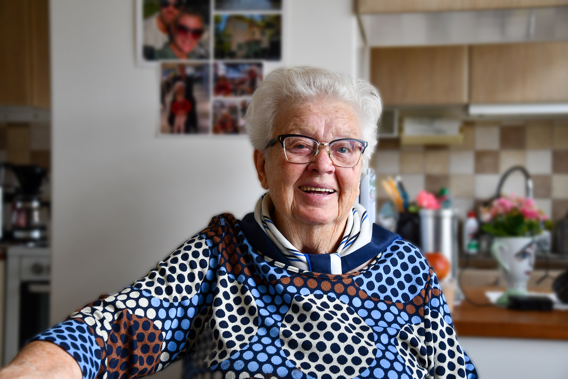 En äldre senior kvinna med glasögon ler mot kameran. 