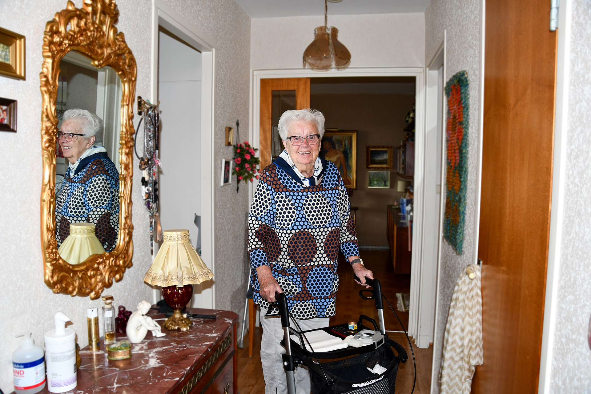 Senior kvinna står upp med stöd av sin rullator. 