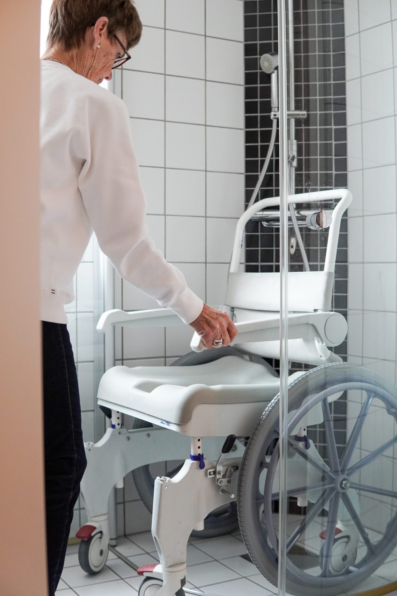 En person ställer i ordning en duschstol i en dusch.