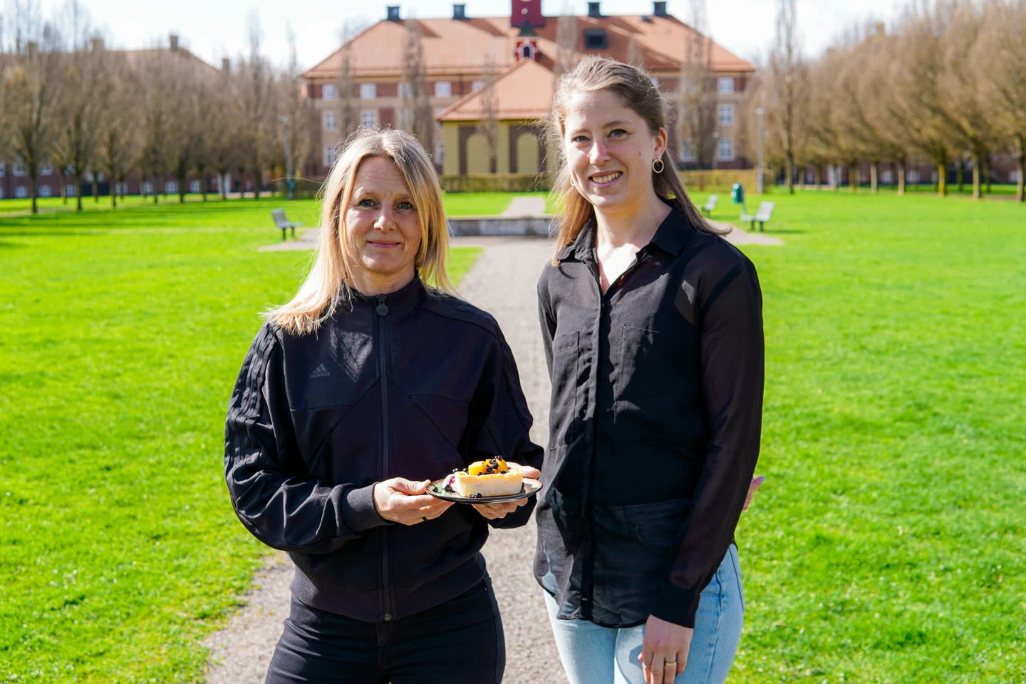 Teresa och Cornelia, dietister på vård- och omsorgsförvaltningen står i en park och håller upp en ostkaka för kameran.