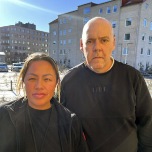 En medelålders man och en kvinna i 30-årsåldern står intill varandra och tittar in i kameran.