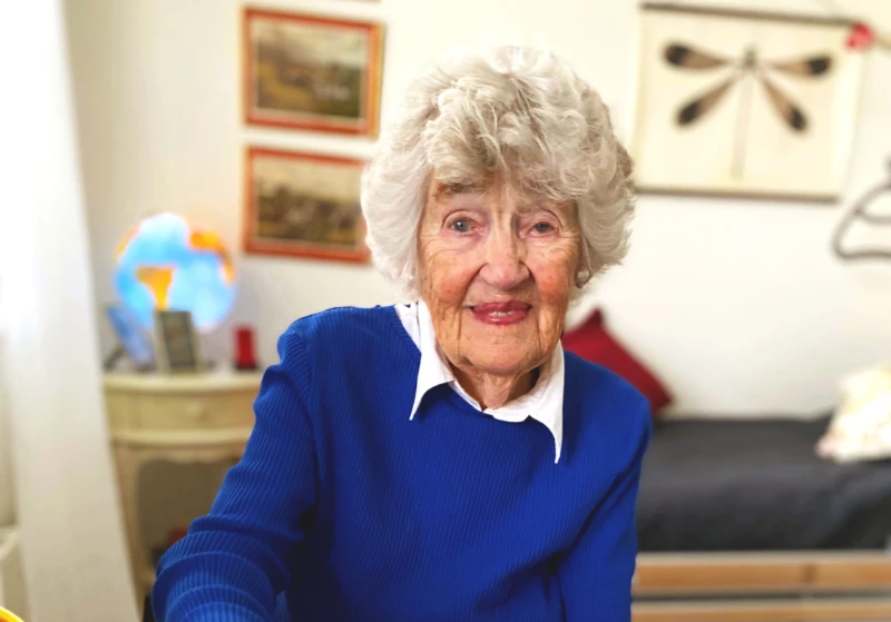 Äldre kvinna tittar in i kameran och ler