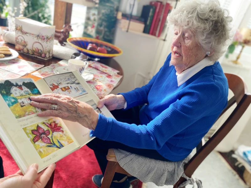 Äldre kvinna håller i en uppslagen bok