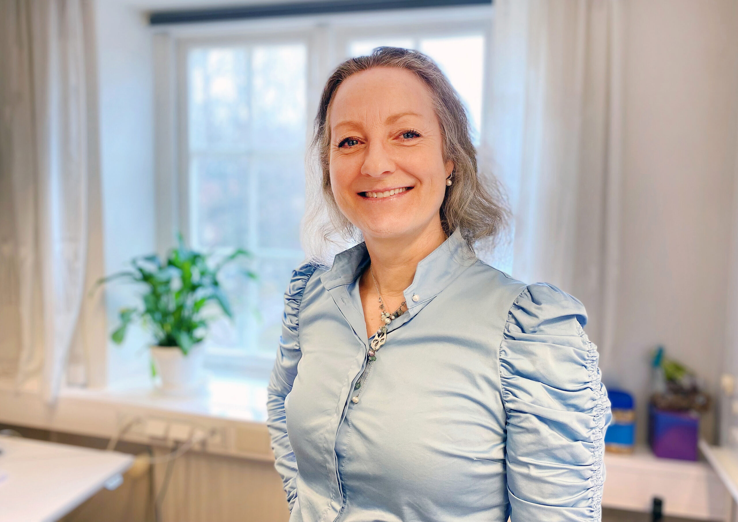 En kvinna ler och tittar in i kameran.