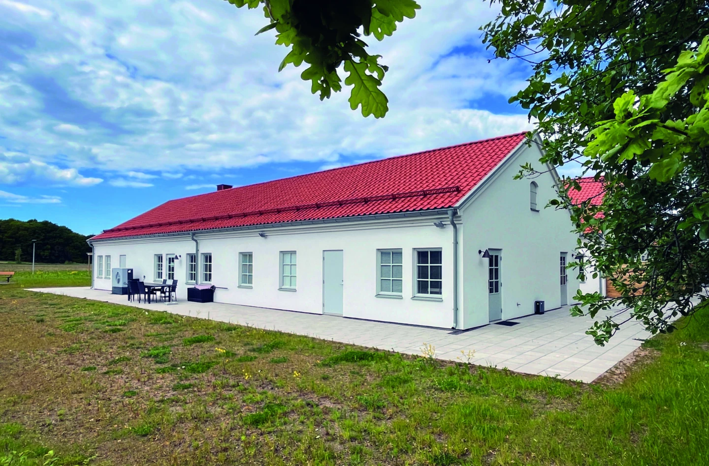 Huskropp med vita väggar och orange tak ligger på en gräsmatta