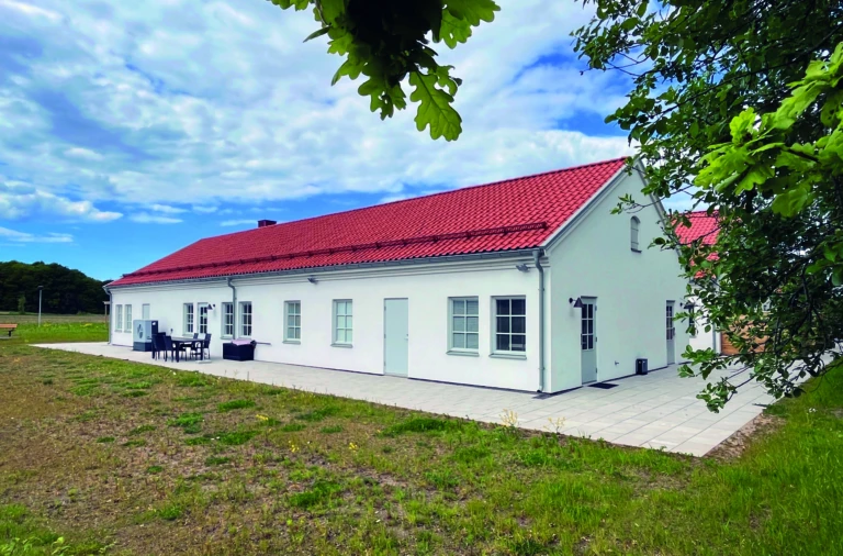 Huskropp med vita väggar och orange tak ligger på en gräsmatta