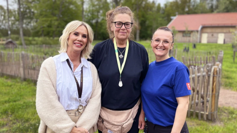 Tre kvinnor står utomhus, tittar in i kameran och ler.