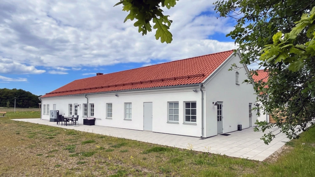 Huskropp med vita väggar och orange tak ligger på en gräsmatta.