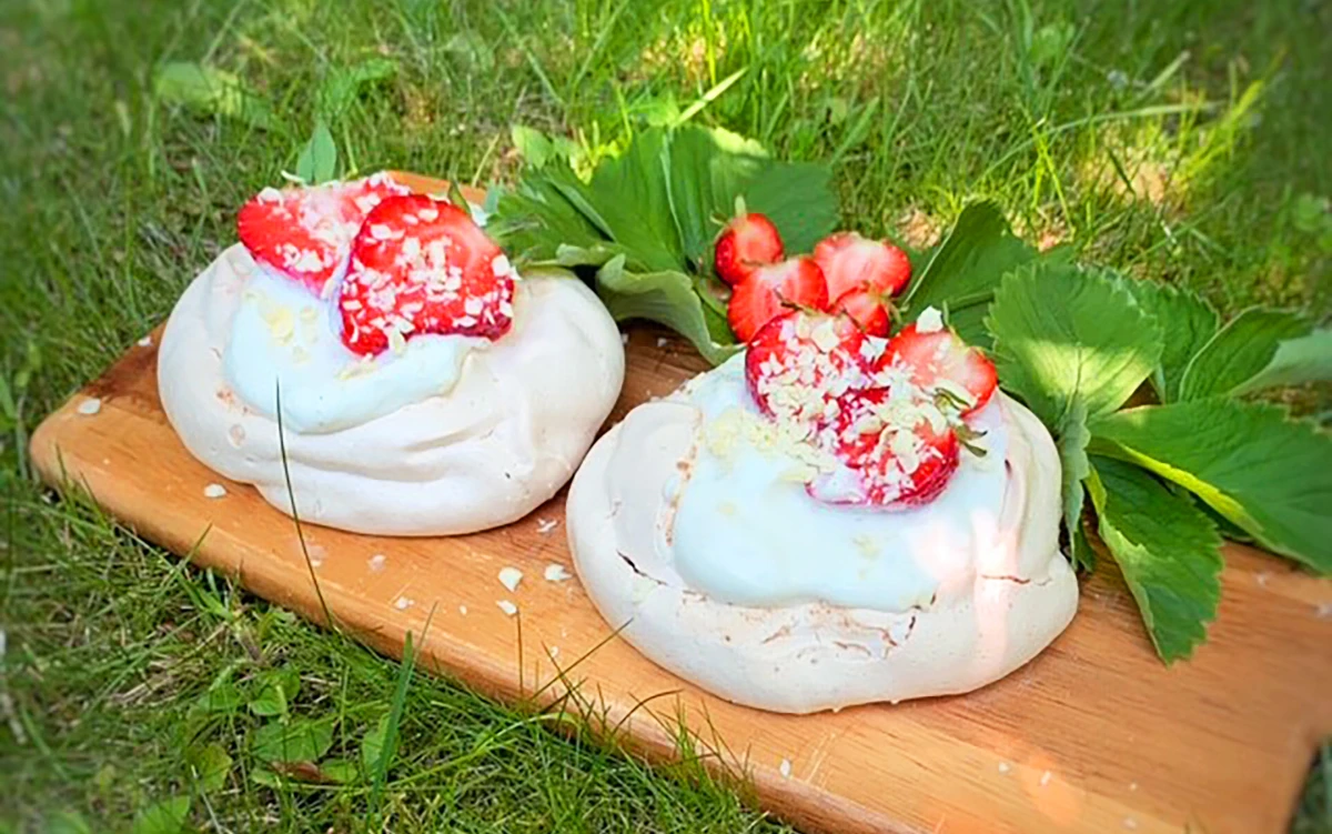 Två marängbakelser på en träbricka i gräset.